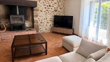 Un salon avec un mur en pierre, une cheminée, un téléviseur et un canapé.