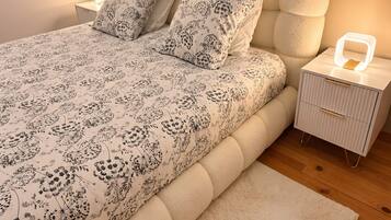 A bed with floral bedding, a bedside lamp, and a nightstand with a lamp.