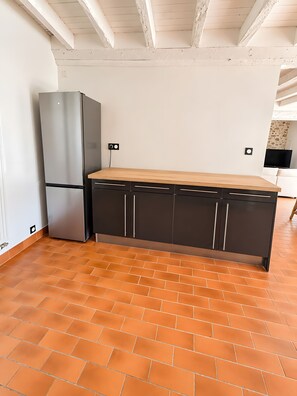Una cocina con refrigerador de acero inoxidable, armarios oscuros y encimera de madera.