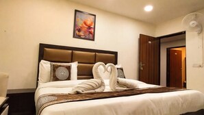 A hotel room with a bed, a bedside table, a wall-mounted artwork, and a ceiling fan. - Hotel SBS Plaza  (New Delhi)