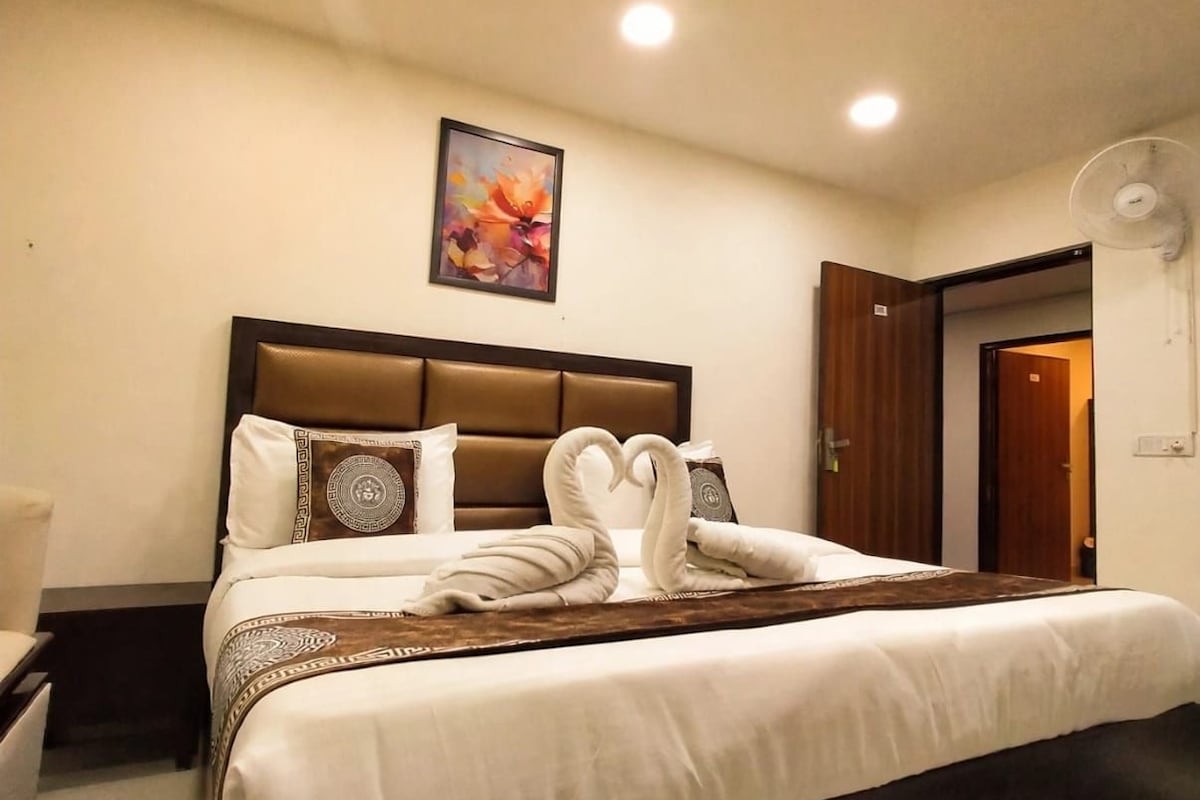Habitación de hotel con cama, mesita de noche, una obra de arte en la pared y ventilador de techo.
