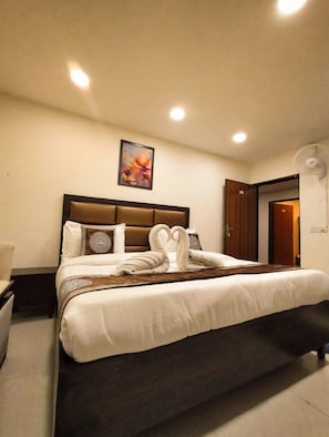 Una camera d'albergo con un letto, un comodino, un'opera d'arte appesa al muro e una ventola a soffitto.