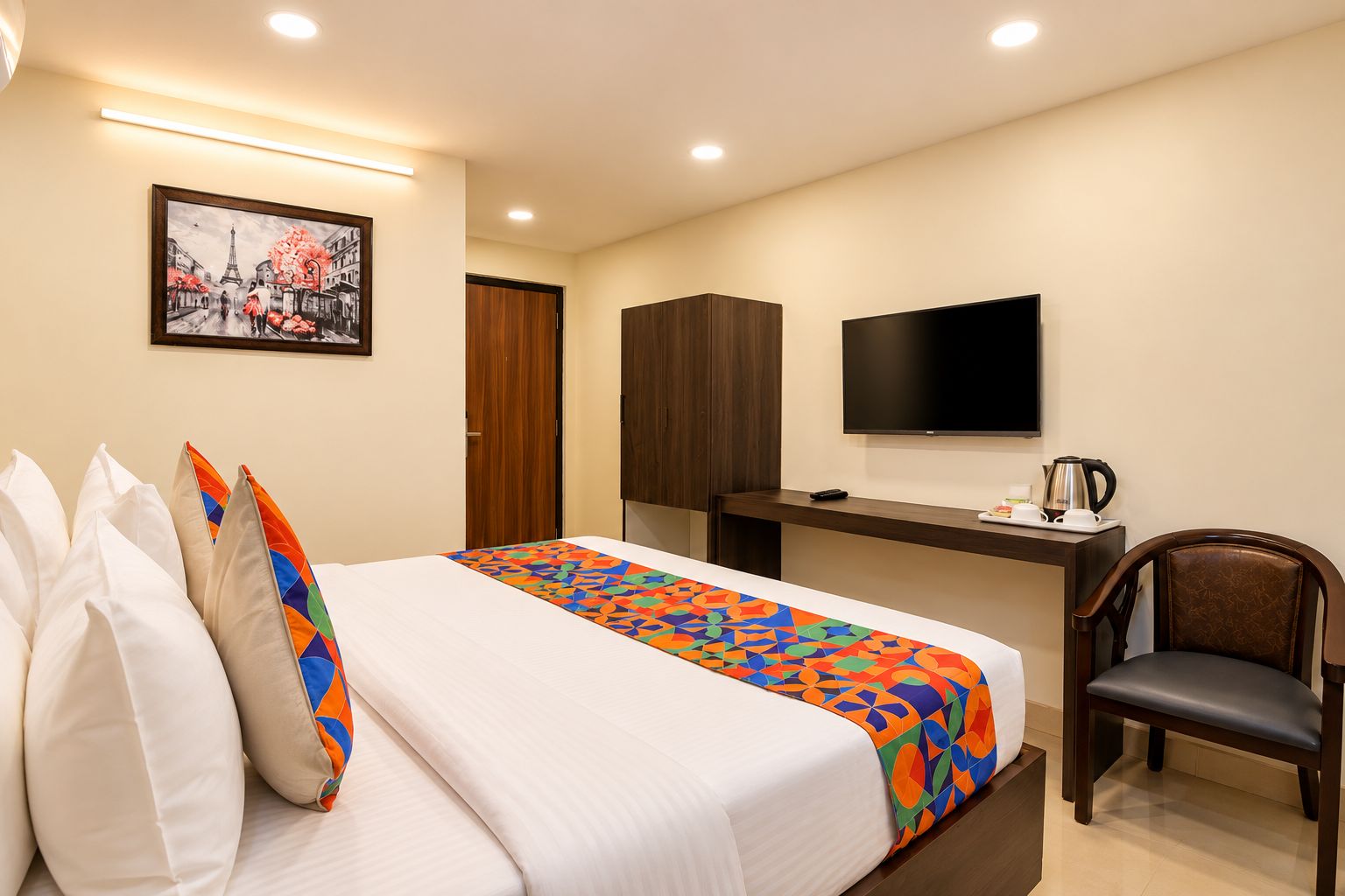 Una habitación de hotel con cama, escritorio, silla, televisión y un cuadro en la pared.
