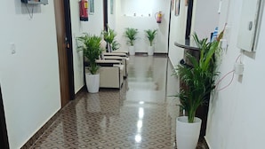 A hallway with patterned flooring, potted plants, and a fire extinguisher on the wall. - Hotel SBS Plaza  (New Delhi)