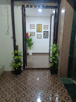 A reception area with a patterned floor, framed pictures on the wall, and potted plants. - Hotel SBS Plaza  (New Delhi)