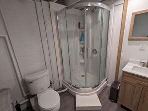 Ein modernes Badezimmer mit einer gläsernen Duschkabine, einer Toilette und einem Waschbecken.