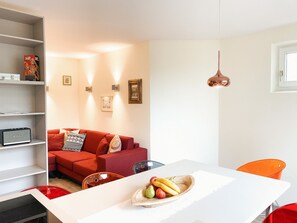 A modern living space with a white dining table, a red sofa, and a fruit bowl. - Chesa Montana - Top 101 (Maria Alm am Steinernen Meer)