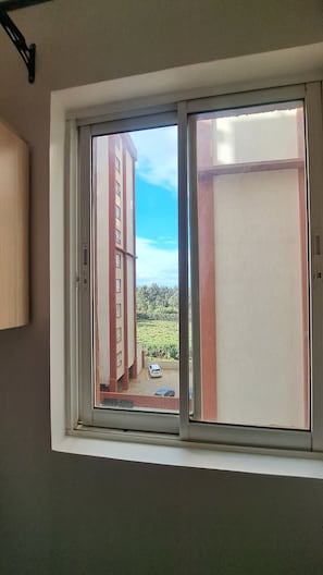 Una finestra con vista su un edificio e un'area di parcheggio.