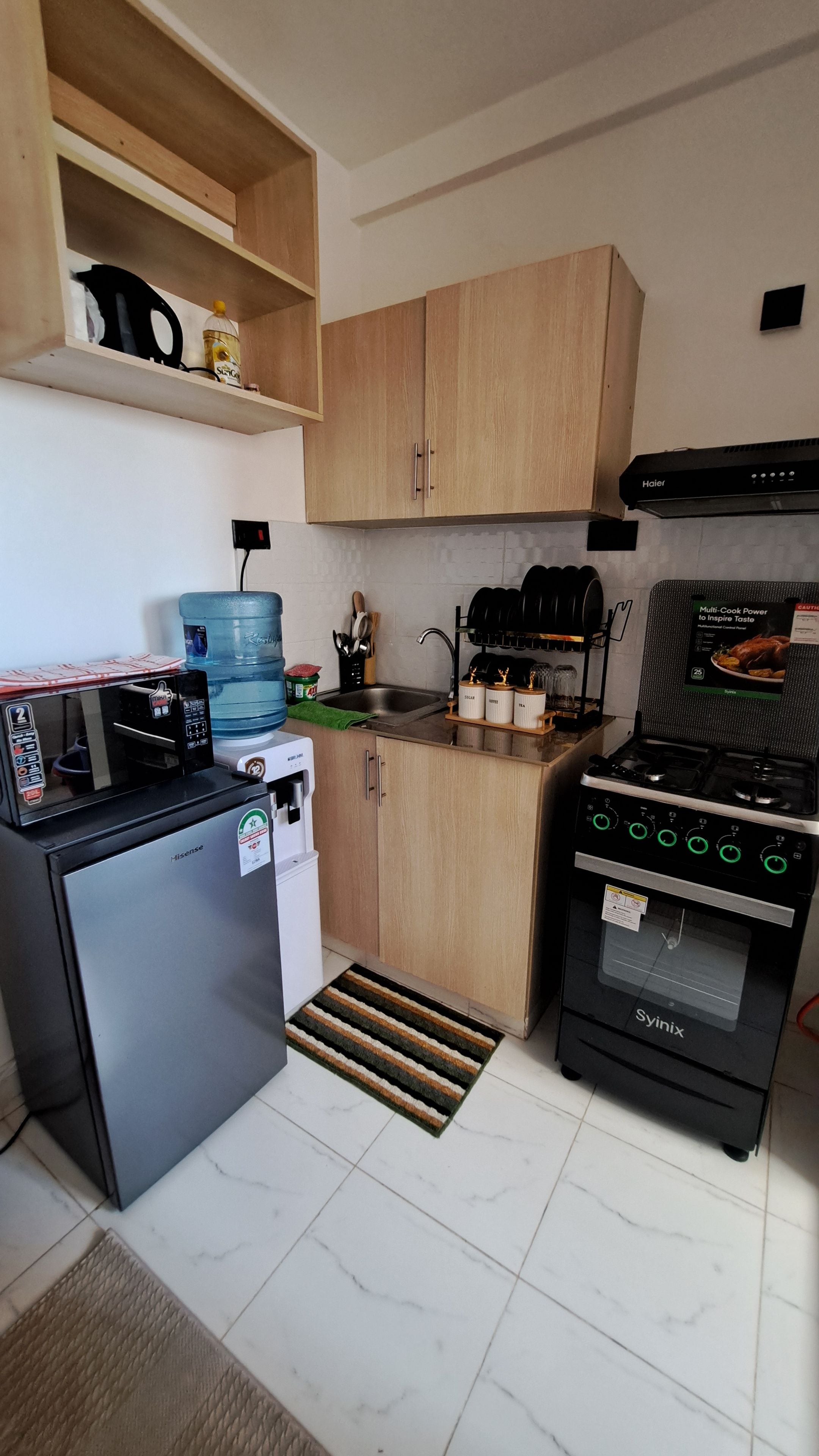 Une cuisine compacte équipée d’un réfrigérateur, d’un four à micro-ondes, d’une cuisinière et d’un distributeur d’eau.