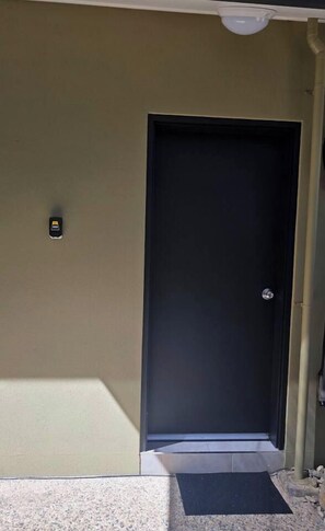 A closed door with a small step leading up to it, a doormat, and a light fixture above. - Lush Getaway, Smithfield (Smithfield)
