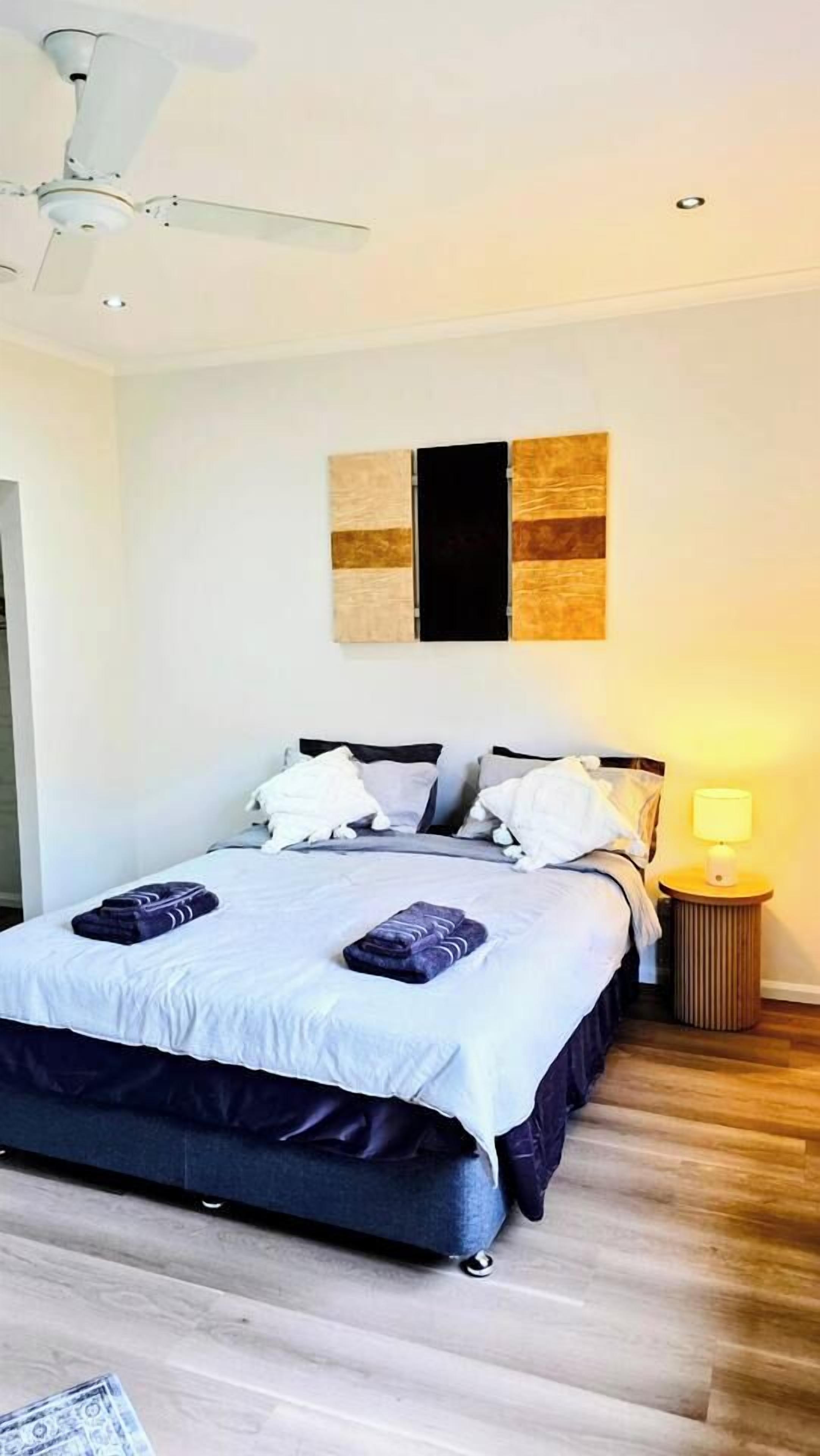 A bedroom with a bed, pillows, a bedside lamp, and a ceiling fan.