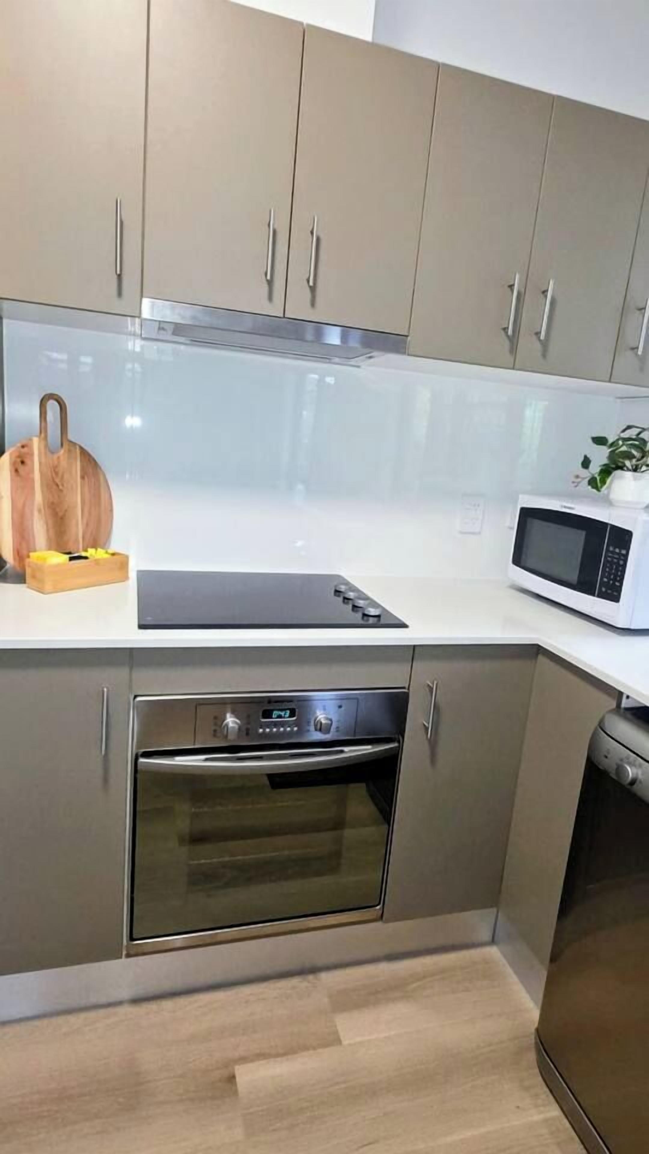 A modern kitchen with a microwave, oven, and a cutting board on the countertop.