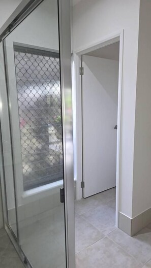 A room with a sliding glass door leading to a balcony, a white door, and a tiled floor. - Lush Getaway, Smithfield (Smithfield)
