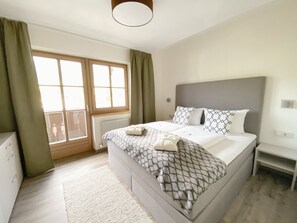 A bedroom with a bed, a nightstand, a window with curtains, and a radiator. - Chesa Montana - Top 204 (Maria Alm am Steinernen Meer)