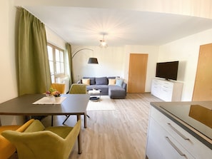 A modern living room with a dining area, a sofa set, a television, and a kitchen area. - Chesa Montana - Top 204 (Maria Alm am Steinernen Meer)