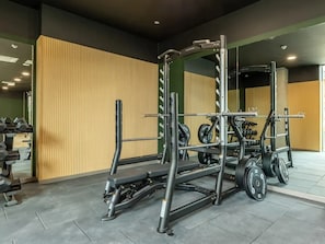 Ein Fitnessraum mit Hantelgestell, Bankdrücker und unterschiedlichem Gewicht.