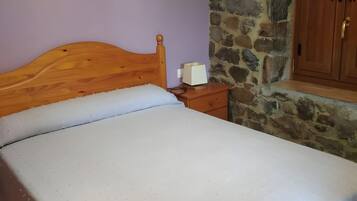Un dormitorio con cama de madera, pared de piedra y armario de madera.