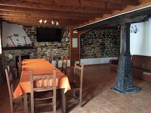 A rustic interior with a stone fireplace, wooden dining table, and a stone pillar.