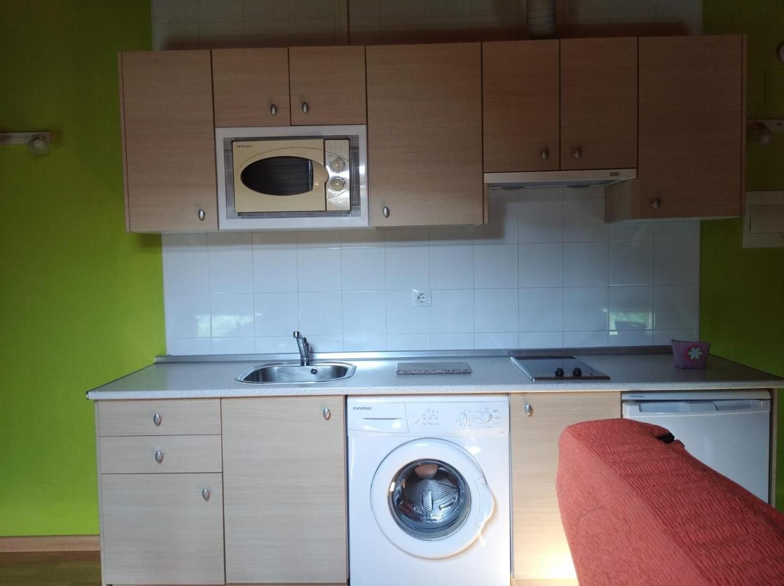 Una cocina compacta con microondas, lavaplatos y lavadora.