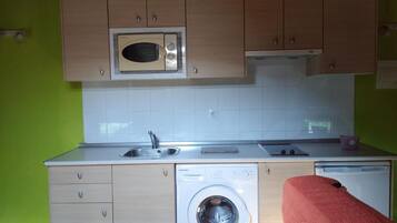 Una cocina compacta con microondas, lavaplatos y lavadora.