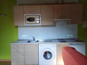 Una cocina compacta con microondas, lavaplatos y lavadora.