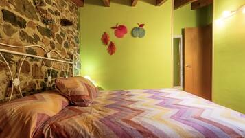 A room with a bed, a stone wall, and a green wall with leaf decorations.