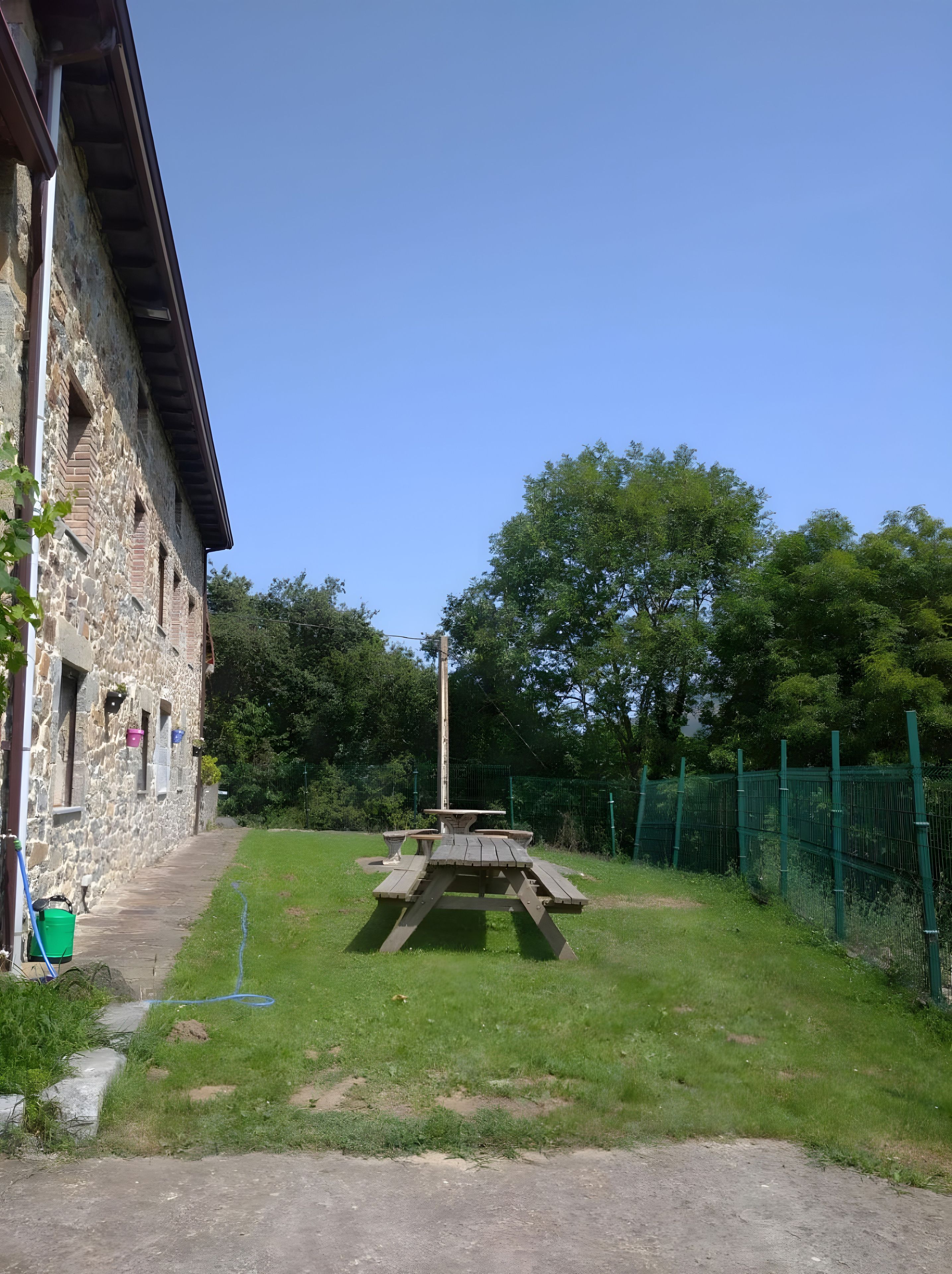 Un edificio de piedra con una mesa de picnic en un área verde.