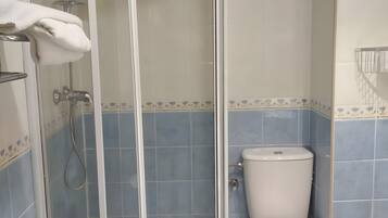 Un baño con ducha envuelta en vidrio, un inodoro y un lavamanos.