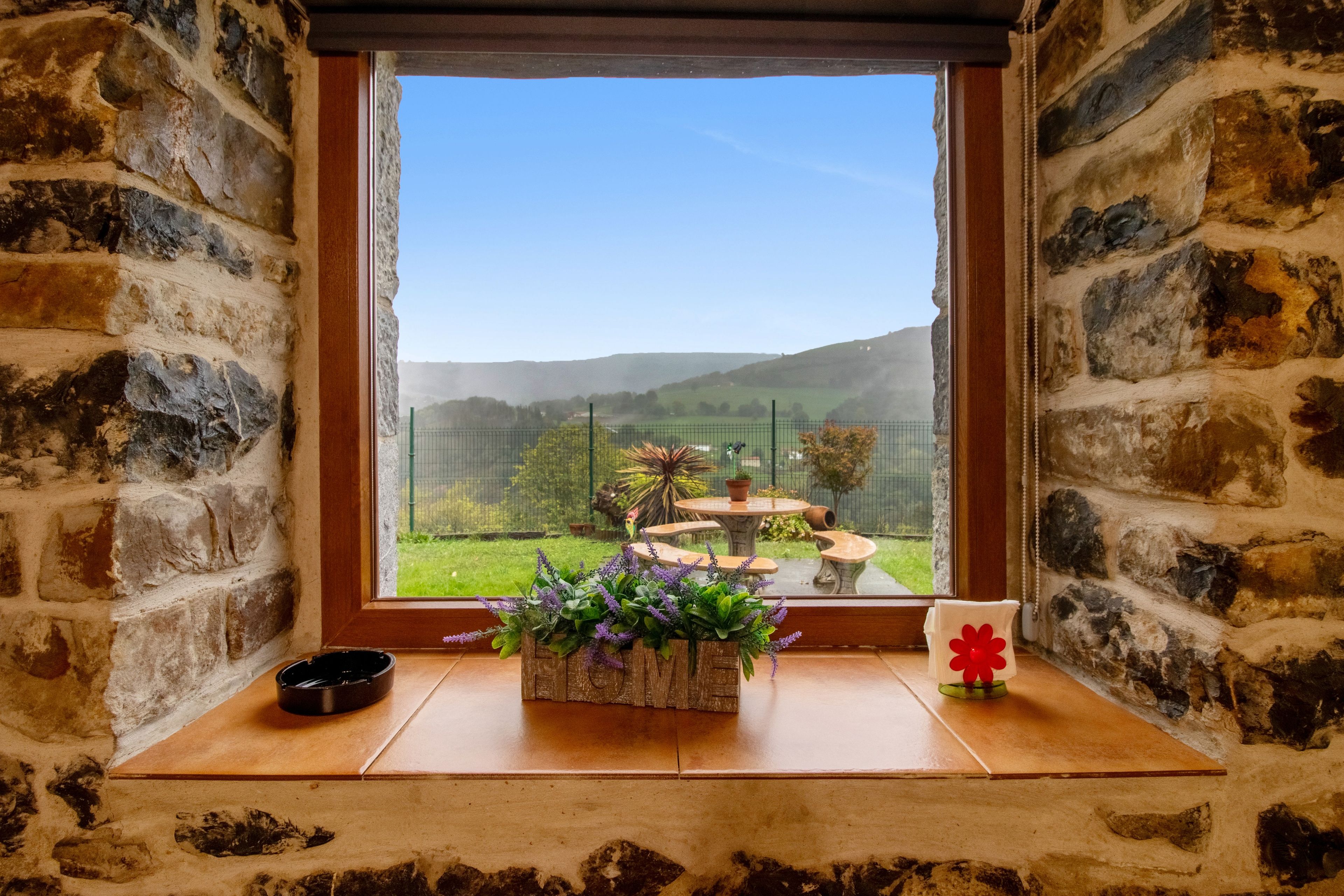 Un muro de piedra con una ventana que da a un jardín.