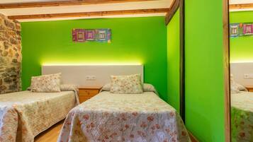 Una habitación con dos camas, una pared de piedra y una pared verde con un cuadro enmarcado.