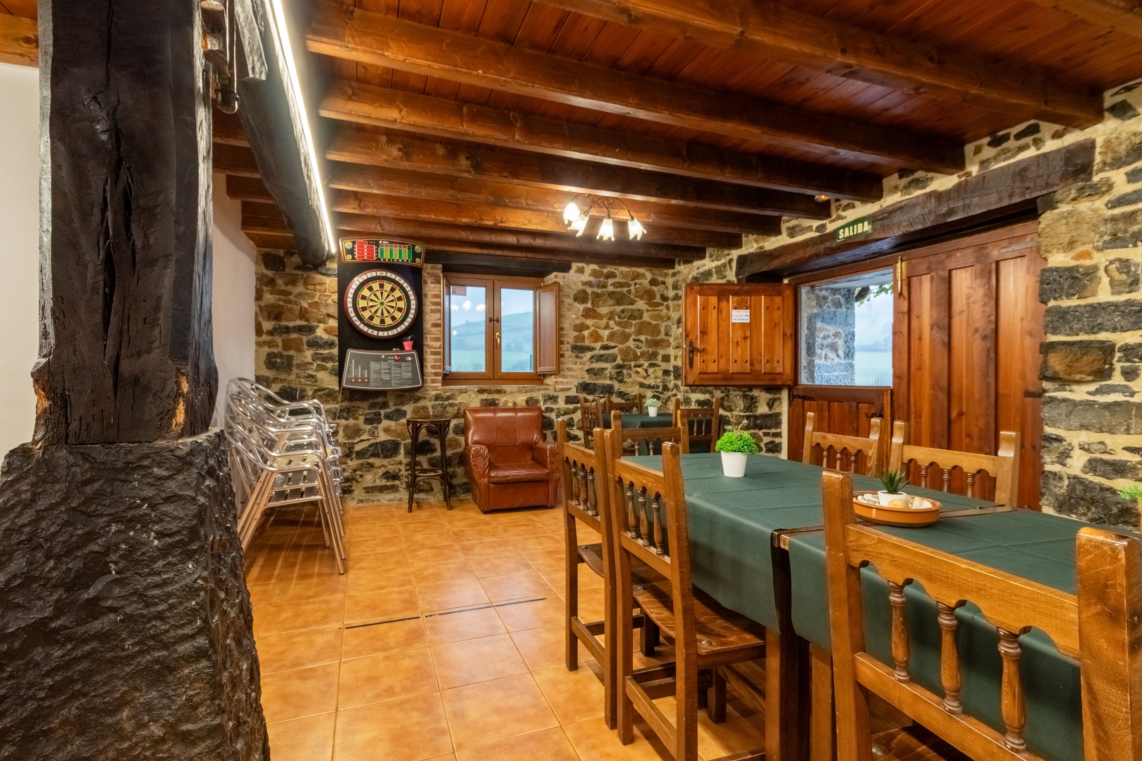 Un comedor rústico con paredes de piedra, muebles de madera y un dardo.