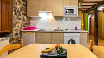 Une cuisine compacte avec des meubles en bois, un four à micro-ondes et un lave-linge encastré.