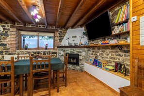 Une pièce chaleureuse avec une cheminée en pierre, des meubles en bois, un téléviseur et une bibliothèque.