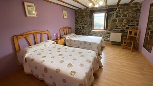Una habitación con dos camas, una pared de piedra, un ventanal y techo de madera.