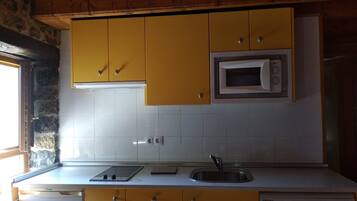 Cocina compacta con armarios amarillos, microondas integrado, fregadero y lavavajillas.