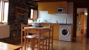 Una cocina funcional con lavadora, mesa de comedor de madera y sillas.