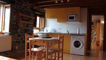 Une cuisine de taille réduite équipée d’un lave-linge, d’une table à manger en bois et de chaises.