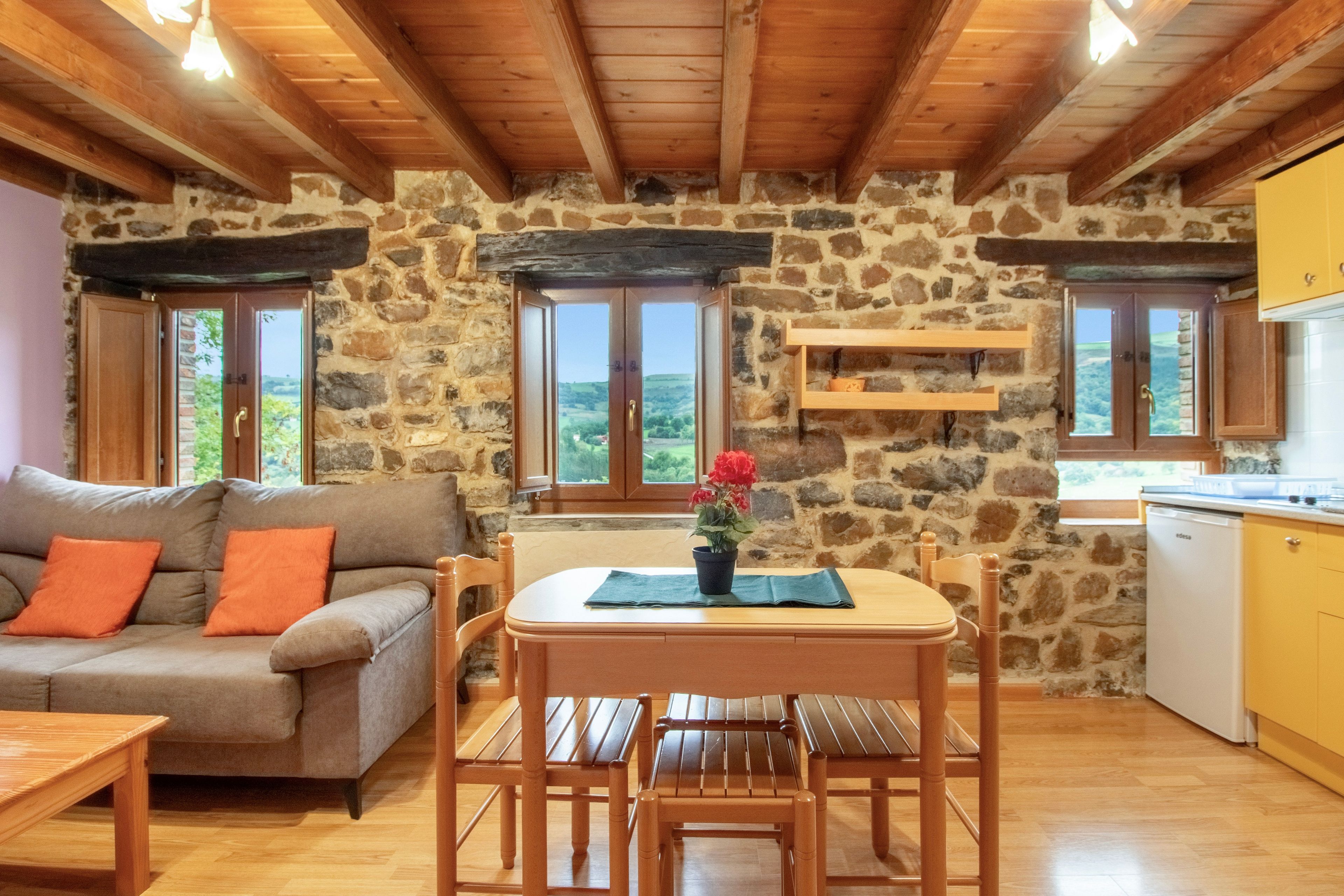 Un interior acogedor con pared de piedra, muebles de madera y vistas a través de las ventanas.