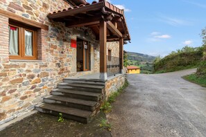 A stone building with a wooden porch and steps leading to a door.