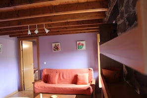 Una sala de estar acogedora con techo de madera, pared morada y sofá rosa.