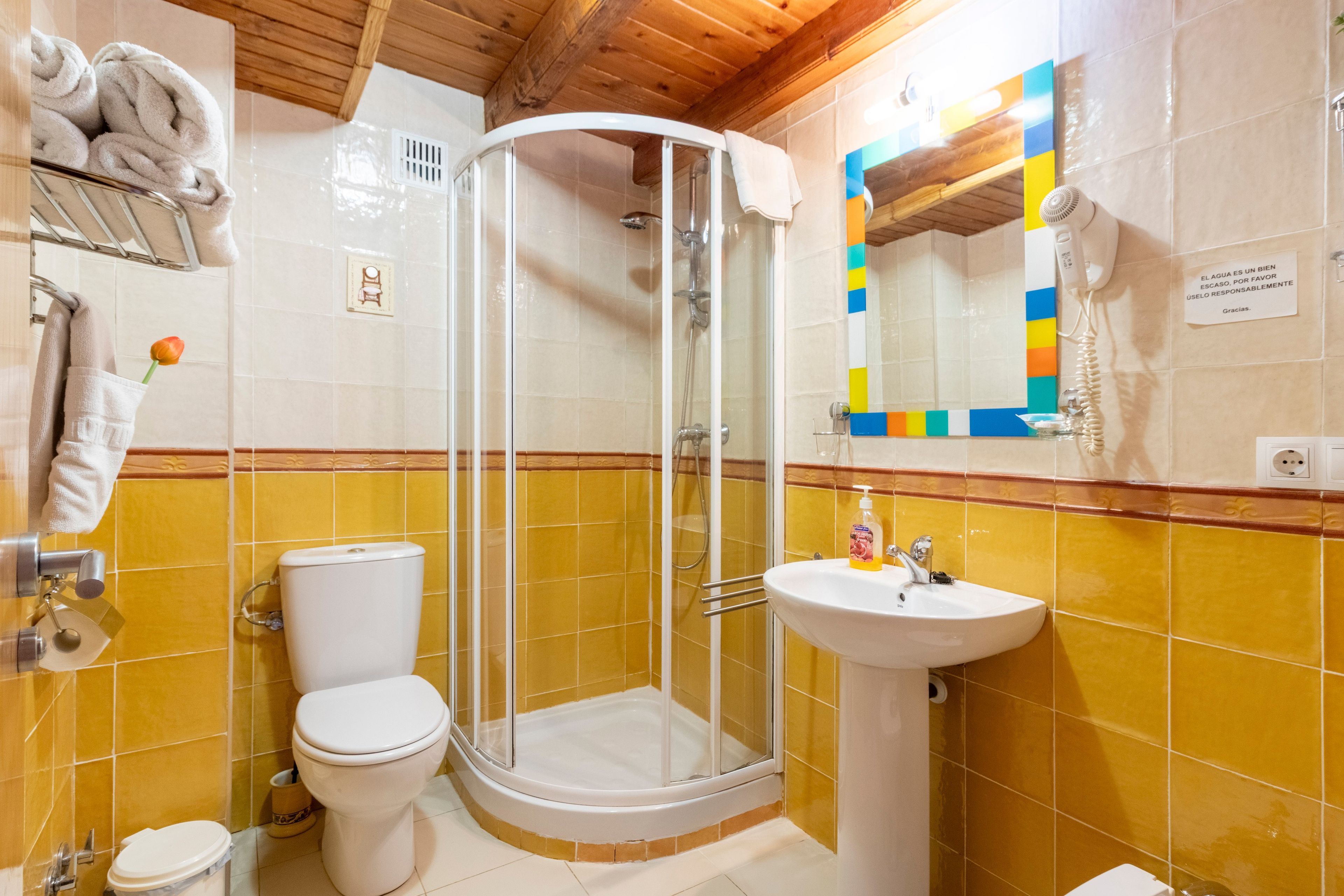 Un baño con ducha envuelta en vidrio, inodoro y lavamanos.