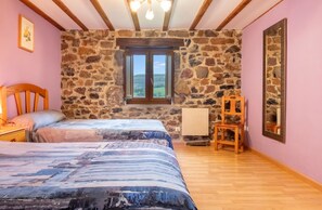 A bedroom with a stone wall, a wooden bed, a chair, and a large mirror.