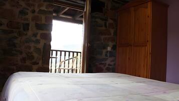 Une chambre à coucher avec un lit, une armoire en bois et un mur en pierre.