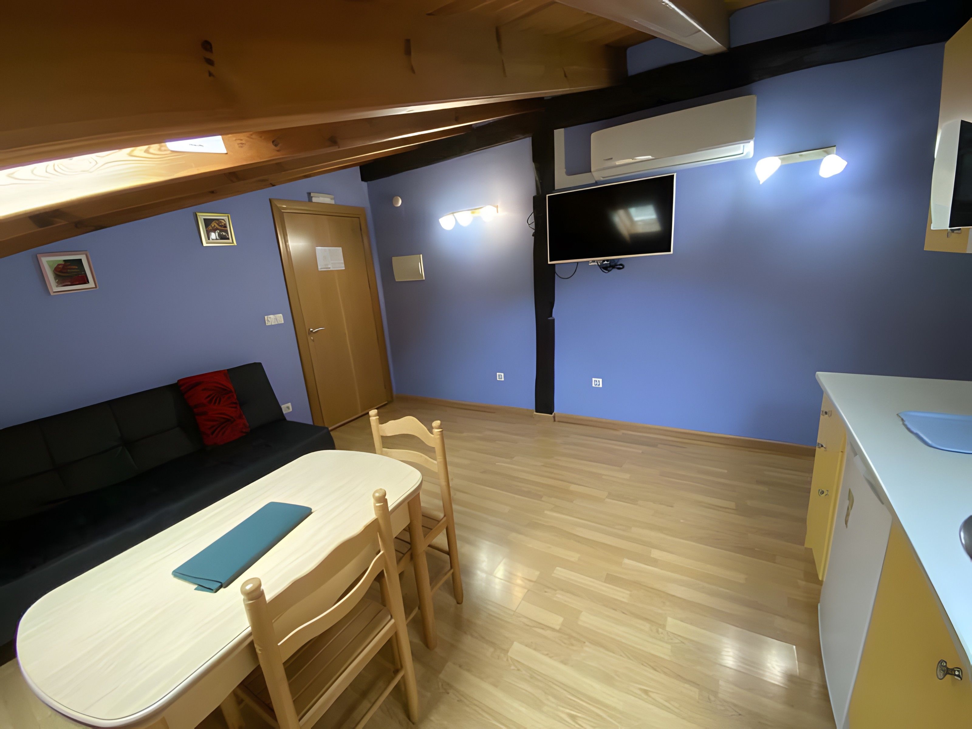 Un espacio habitable compacto con kitchenette, comedor y zona de estar.