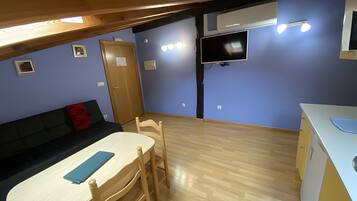 Un espacio habitable compacto con kitchenette, comedor y zona de estar.