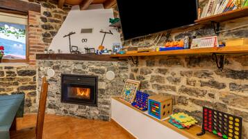 Una sala de estar acogedora con chimenea de piedra, televisión y varios juguetes y libros infantiles en estanterías.