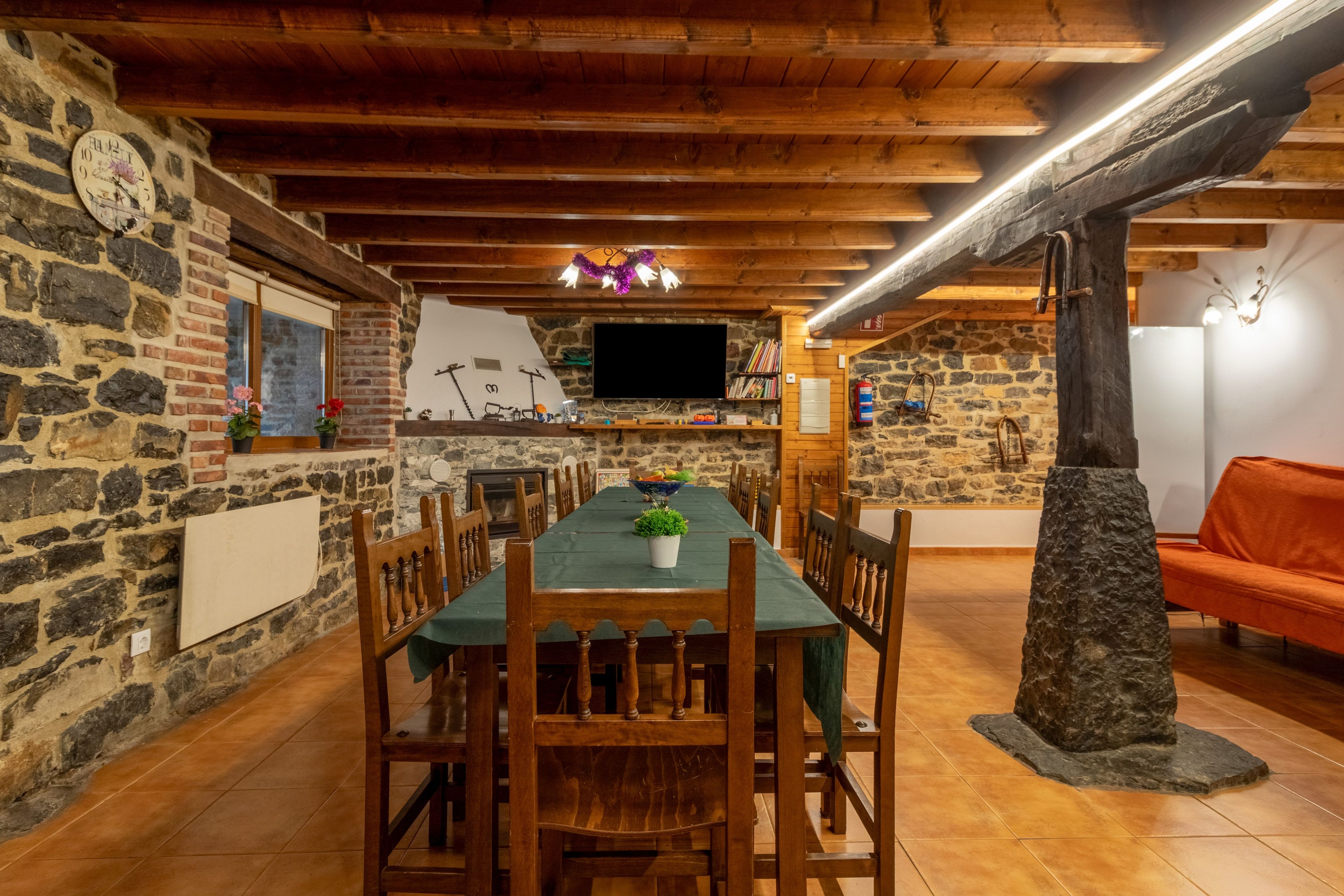 Un espace repas avec une longue table en bois, des murs en pierre et une colonne en pierre.