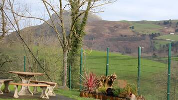 A park with a stone bench, a fence, and a view of rolling hills.