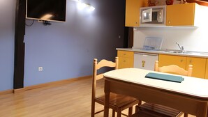 Un comedor con mesa y sillas, un microondas y una pequeña cocina con armarios.