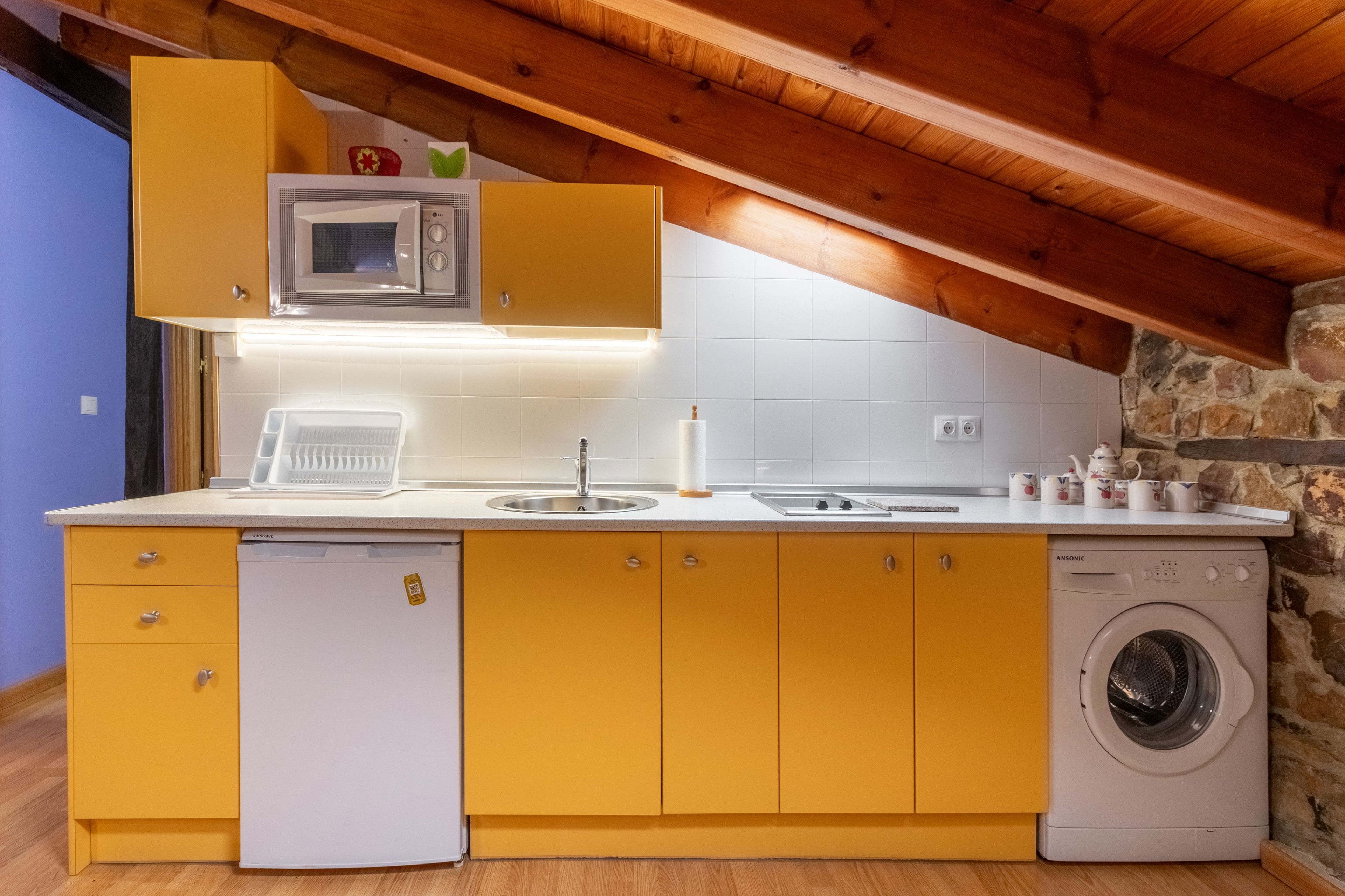Cozinha compacta com máquina de lavar, micro-ondas e pia.